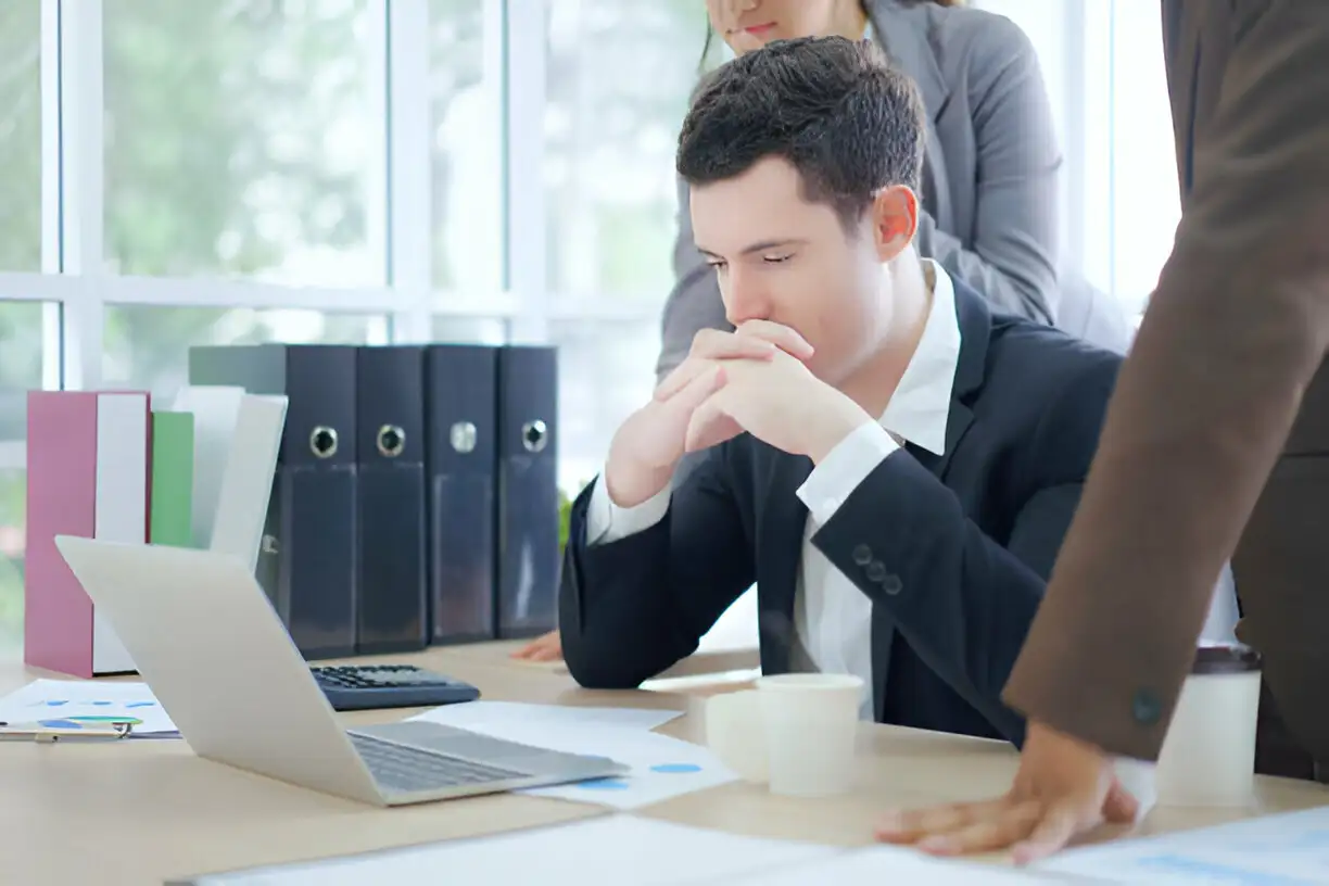 Hombre preocupado en su oficina, enfrentando una posible terminación laboral. Conocer los derechos del trabajador es fundamental para su protección.